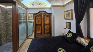 Quarto com uma cama grande, um guarda-roupa, uma porta de vidro para uma varanda e um teto com claraboia.