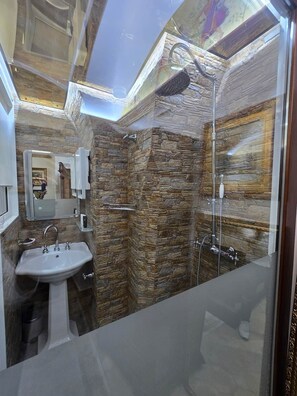 A bathroom with a stone wall, a sink, and a shower. - The Etrurian Rapsody (Rome)