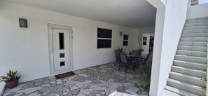 A covered patio with a stone floor, a white door, and a table with chairs. - Come for the beaches? Villa Marcos, unique 2-bedrooms apartment Curacao with AC (Willemstad)