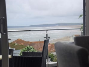 Blick von einem Balkon auf ein Gewässer mit einer fernen Küste.