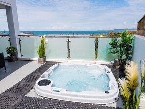 Una vasca idromassaggio su un balcone con vista mare.