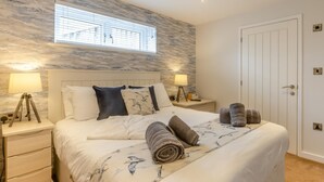Ein Schlafzimmer mit einem Bett, zwei Nachttischen, einem Fenster und einer Tür.