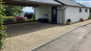 A building with a covered porch, a door, and a gravel driveway. - 2 Bed in Cinderford (oc-65670) (Littledean)