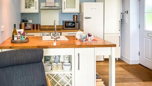 A modern kitchen with white cabinets, a wooden countertop, a built-in microwave, and three pendant lights. - 2 Bed in Cinderford (oc-65670) (Littledean)