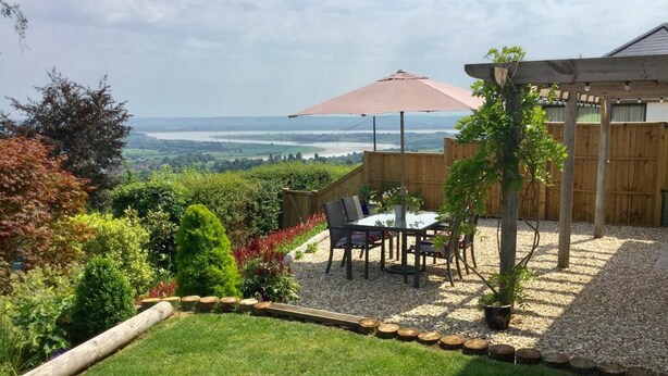 A patio with a table and chairs, a pergola, and a view of a river. - 2 Bed in Cinderford (oc-65670) (Littledean)