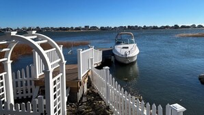 Un bateau était amarré à un quai, bordé d’une clôture blanche, d’où l’on avait une vue dégagée sur l’eau.