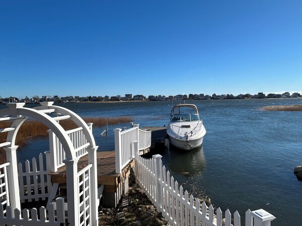 A boat docked at a pier with a white fence and a clear view of the water.
