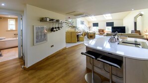 Una cucina moderna con isola centrale, pavimento in legno e zona pranzo con divano e sedie.