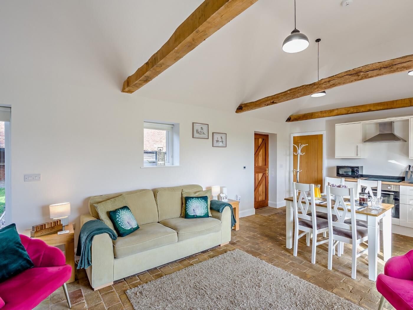 Un salon confortable avec un canapé, une table à manger et des chaises, un coin cuisine et une fenêtre.