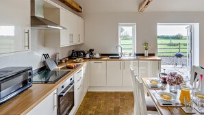 Eine moderne Küche mit weißen Schränken, einer Holz Arbeitsplatte, einem eingebauten Backofen und einem Essbereich mit einem für das Frühstück gedeckten Tisch.