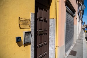 A yellow building with a closed shutter, a brown door, and a sign indicating 'CASA VACANZA VIRENOZI 155.' - A comfortable 65 sqm apartment, suitable for up to 3 people, located on the first floor of a building without an elevator (access via stairs).The property is strategically located just 50 meters from the hospital.Piacenza city center is easily accessible (Piacenza)