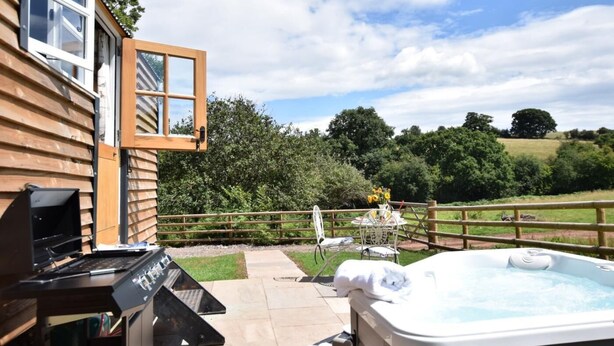 A wooden cabin with a hot tub, outdoor seating, and a view of the countryside. - 1 Bed in Hereford (oc-78641) (Twyford)