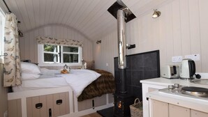 A cozy room with a bed, a fireplace, a window with curtains, and a kitchenette. - 1 Bed in Hereford (oc-78641) (Twyford)