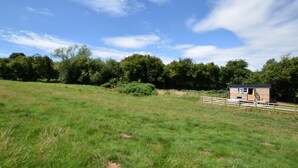 A grassy field with a small wooden cabin and a wooden fence. - 1 Bed in Hereford (oc-78641) (Twyford)