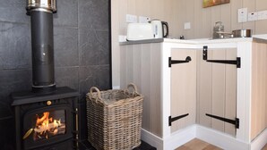 A kitchen with a wood-burning stove, a woven basket, and a painting of a pig on the wall. - 1 Bed in Hereford (oc-78641) (Twyford)