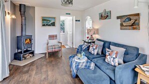 En hyggelig stue med pejs, en blå sofa og et spiseområde med et bord dækket til to.