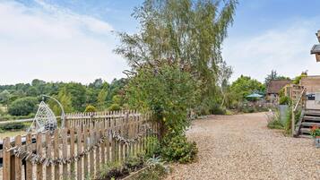 A gravel driveway leading to a wooden fence with a hanging decorative item.