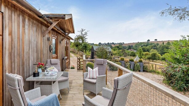 Eine Holzterrasse mit Korbmöbeln und Blick auf eine üppige Landschaft.
