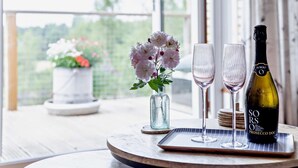 Ein Tisch mit einer Weinflasche, zwei Gläsern und einer Blumenvase.