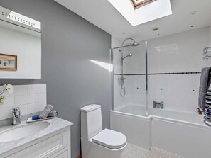 Une salle de bain moderne avec un puits de lumière, une douche, des toilettes et un lavabo.