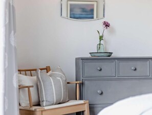 A bedroom with a wooden bed, a grey dresser, and a small vase with a flower on top.