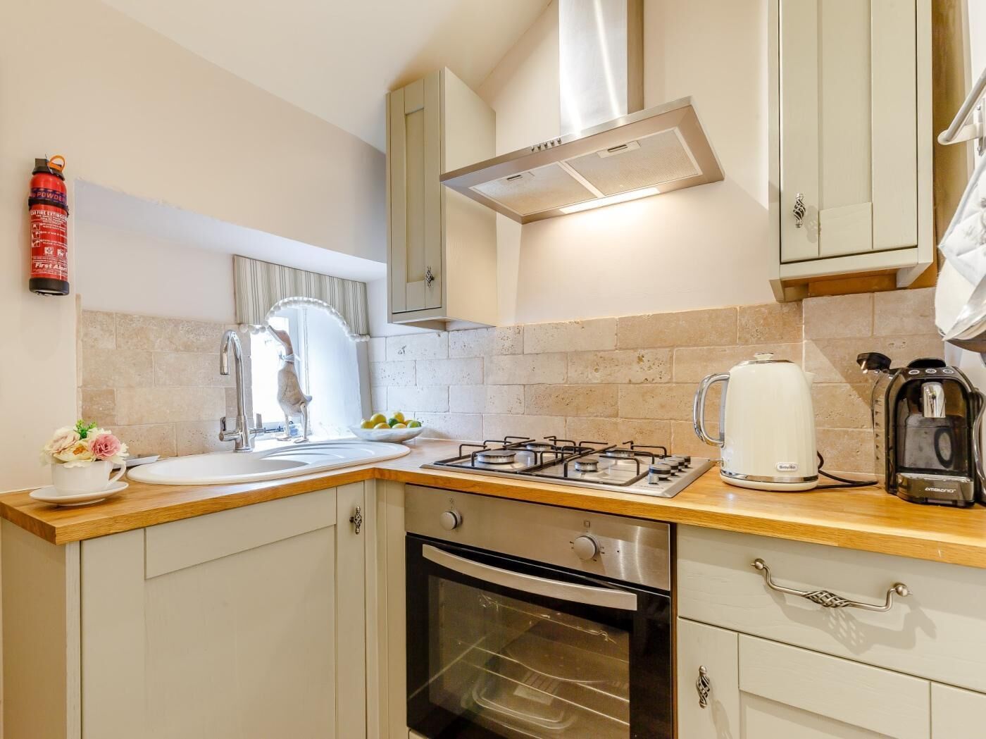 A kitchen with a gas stove, oven, sink, and a coffee maker.