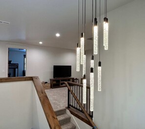 Eine Treppe mit Holzwangen und Teppichboden, die zu einem Raum mit einem Flachbildfernseher und einer Holz-Unterhaltungsecke führt.