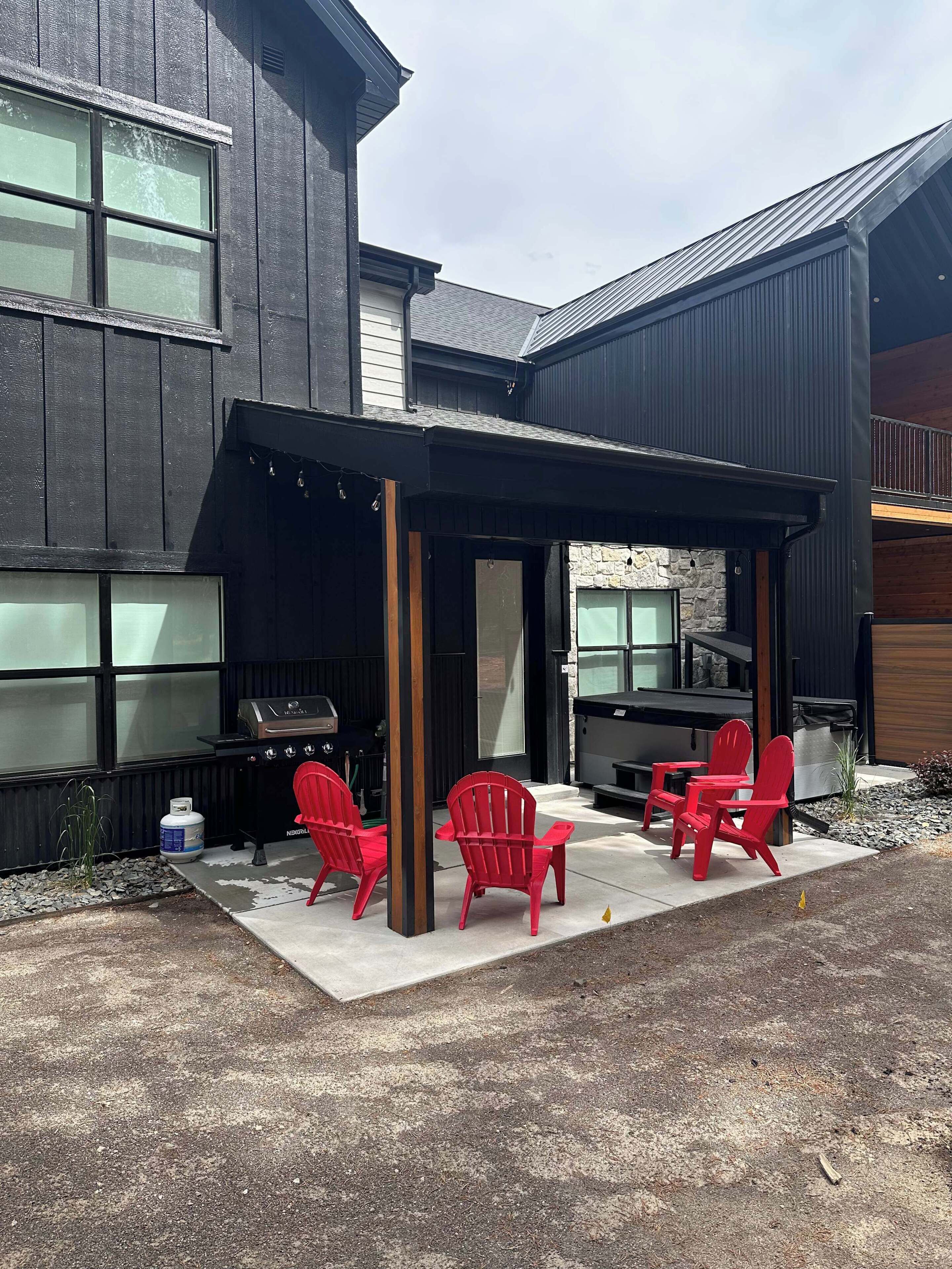 Un espace extérieur abrité avec des chaises rouges et un barbecue.