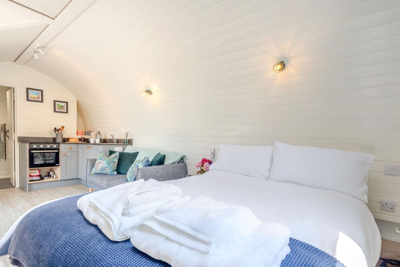 Une chambre avec un grand lit, un coin cuisine et un plafond en pente.