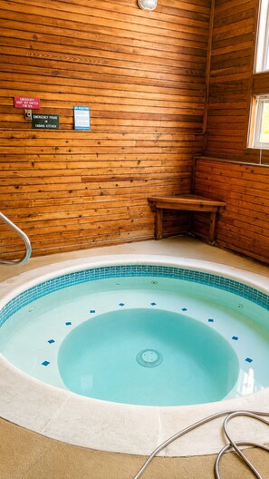 Ein Holzblockbau-Innenraum mit Whirlpool, Holzwänden und einer kleinen Holzbank.