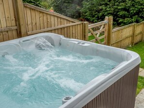 A hot tub with water flowing, surrounded by a wooden fence and greenery. - 3 Bed in Matlock (oc-78717) (Crich)