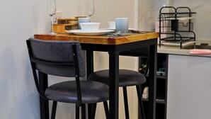 A small dining area with a wooden table and two black chairs. - Beautiful and well furnished one bedroom apartment in a well secured area. (Nairobi)