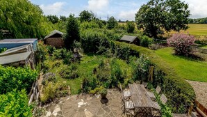A garden with a patio, wooden furniture, and a stone pathway. - 3 Bed in North Walsham (oc-78708) (Honing)