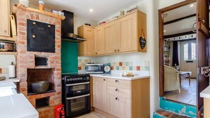 A kitchen with a brick oven, a microwave, and wooden cabinets. - 3 Bed in North Walsham (oc-78708) (Honing)