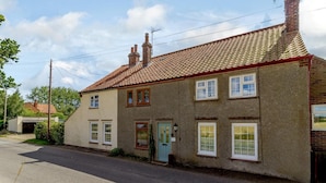 A two-story house with a tiled roof, a front door, and a garage. - 3 Bed in North Walsham (oc-78708) (Honing)