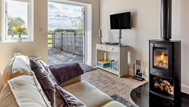 Uma sala de estar aconchegante com um sofá, televisão, lareira e vista para o exterior.