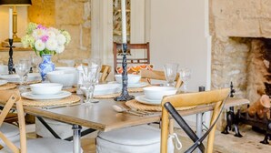Una mesa de comedor dispuesta con platos blancos, vasos y un florero con flores.