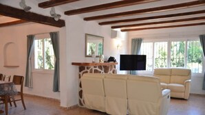 Ein Wohnzimmer mit einer Couch, einem Fernseher und einem Essbereich mit Stühlen und einem Tisch.