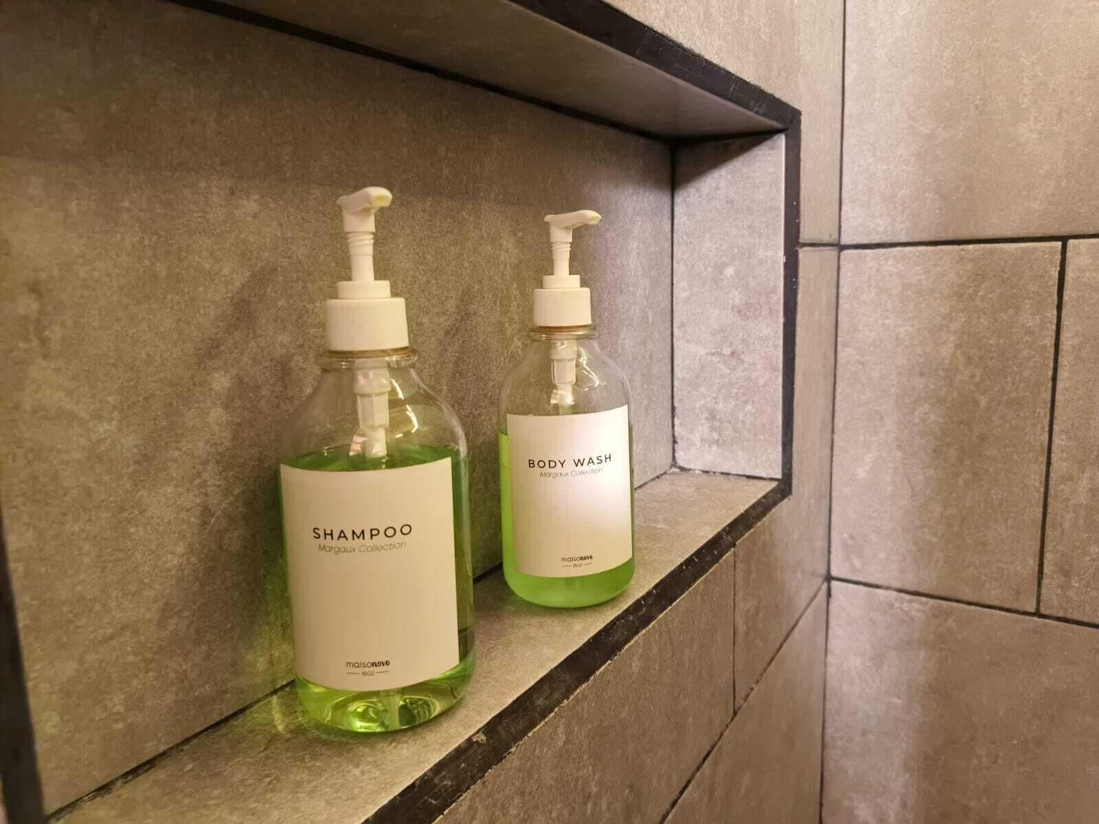 Zwei Flaschen Duschgel und Shampoo stehen auf einem Regal.