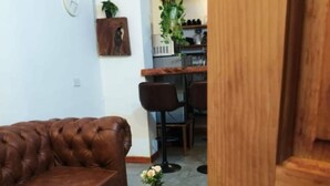 Un sofá de cuero marrón, una mesa de centro de madera con una planta, y una puerta moderna con cerradura digital.