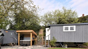 En campingplads med et træskur, en grå metalbygning og et lille haveområde.