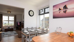 Un comedor con una mesa de madera, sillas, un reloj y un frutero.