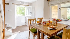 Comedor con mesa de madera, sillas y ventana con vista a follaje.