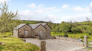 A stone building with a paved courtyard and a stone wall. - 2 Bed in St. Austell (oc-79594) (Coombe)