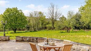 An outdoor patio with stone flooring, wooden chairs, and a table set for two. - 2 Bed in St. Austell (oc-79594) (Coombe)