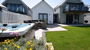 A modern house with a hot tub, outdoor seating, and a well-maintained lawn. - 4 Bed in Bideford (oc-72587) (Northam)