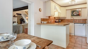 Una cucina compatta con isola centrale, mobili bianchi e zoccolo in piastrelle.