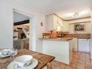 A compact kitchen with a central island, white cabinetry, and a tiled backsplash. - 3 Bed in Stiffkey (oc-ncc49) (Stiffkey)
