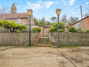 A stone wall, a brick house with a chimney, and a paved entrance with steps. - 3 Bed in Stiffkey (oc-ncc49) (Stiffkey)