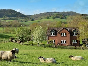 A two-story house with a brick exterior, surrounded by a fenced field with sheep. - 1 Bed in Telford (oc-73319) (Buildwas)